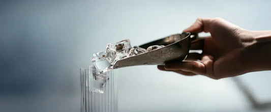 Ice cubes in a scoop being poured into a glass